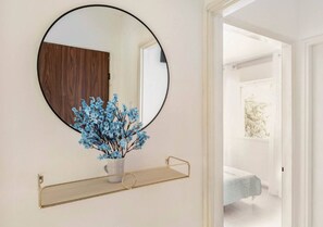 Reflecting serenity, this room features a large mirror, a door, and a window, complemented by a beautiful floral arrangement.