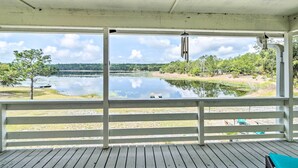 A covered deck with a view of a lake and forest.