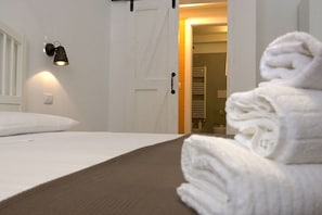 A neatly made bed with a white pillow, a folded white towel on the bed, and a wall-mounted light fixture. - Single-family home in the center of Appartement Cardille (Monopoli)