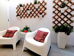 A room with two white chairs, a small round table, and a large potted plant. - Single-family home in the center of Appartement Cardille (Monopoli)
