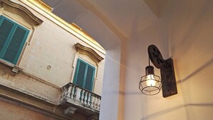 A building facade with a balcony and a wall-mounted light fixture. - Detached house in the center Cardille Apartment (Monopoli)