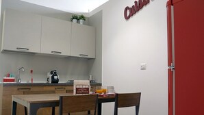 A compact kitchen with a dining area, a red door, and a sign indicating a service area. - Detached house in the center Cardille Apartment (Monopoli)