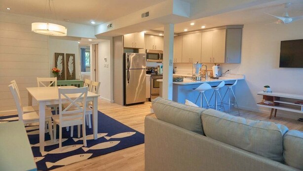 A modern kitchen with stainless steel appliances, a dining area with white chairs, and a living room with a sofa. - 2 Bdrm/2 Bath, Sleeps 6, Pool, Balcony, Wi-Fi, TVs (Ocean City)