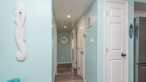 A hallway with teal walls, wooden flooring, and white doors.