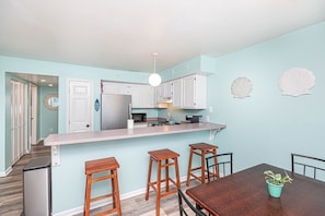 Enjoy meals in this kitchen with white cabinetry, a dining table, and a potted plant.