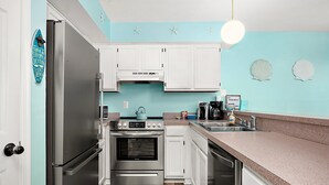 A kitchen with white cabinets, a stainless steel refrigerator, a stove, and a dishwasher.