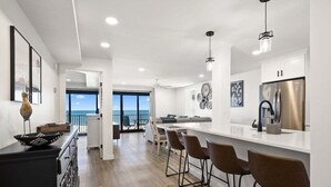 Eine moderne Küche mit einer zentralen Kochinsel, Barhocker und einem Edelstahl-Kühlschrank.