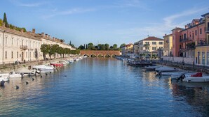 A canal with boats docked along the sides, a bridge in the background, and buildings lining the waterway.