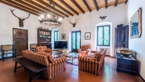 A spacious living room with striped sofas, a wooden ceiling, and antler decorations.