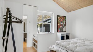 Une chambre à coucher avec un lit, une fenêtre, un tableau et une échelle.