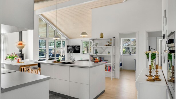 Une cuisine moderne dotée d’un îlot central, de grandes fenêtres et d’un plafond en bois.