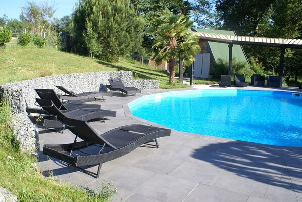 A swimming pool with lounge chairs and a pergola.