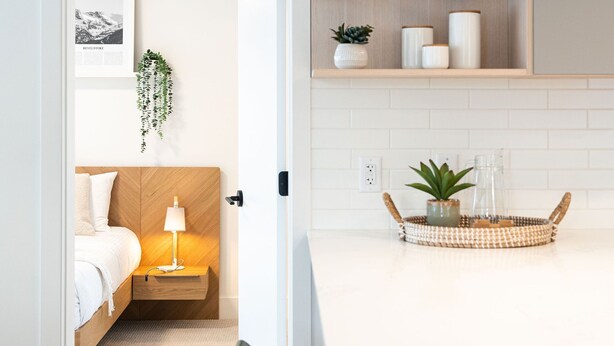 A modern kitchen with a wooden countertop, a hanging light fixture, and a shelf with glassware. - Adanac Revelstoke by Revelstoke Vacations (Revelstoke)