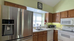 A kitchen with stainless steel appliances, wooden cabinets, a microwave, and a toaster. - 14022 Maple Way (Mercersburg)