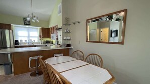 A kitchen with a central island, wooden chairs, and a dining table. - 14022 Maple Way (Mercersburg)