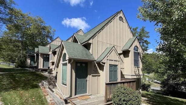 A two-story building with a green door, a small porch, and a gravel driveway. - 14022 Maple Way (Mercersburg)