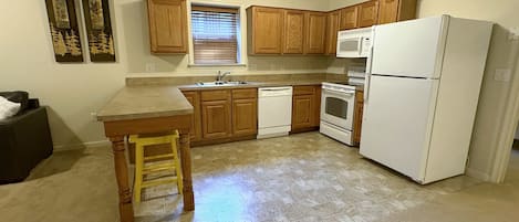 Une cuisine avec des meubles de rangement en bois, un réfrigérateur blanc, une cuisinière et un évier.