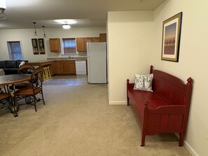 A compact living space with a dining area, kitchen, and a red sofa with a cushion.