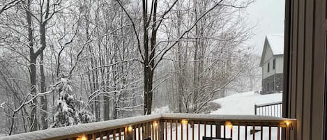 A snow-covered deck with outdoor seating and a view of a snowy landscape.