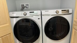 Two Samsung front-loading washing machines in a laundry room with a tiled floor and wooden cabinetry. - UpNorth Getaway with access to ATV UTV Snowmobile Trail (Birchwood)
