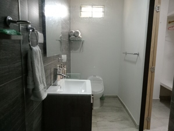 A compact bathroom with a white sink, a toilet, and a small window.