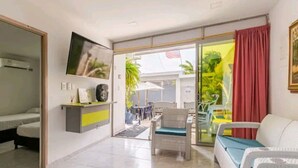 A hotel room with a bed, a sofa, a TV, a desk, and a sliding glass door leading to an outdoor area with a table and chairs. - Casa Playa Arreboles is located in front of the beach, ideal for families. (La Boquilla)