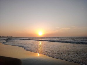 A beach at sunset with waves approaching the shore.