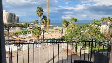 A balcony with a view of a construction site, palm trees, and a building in the background.