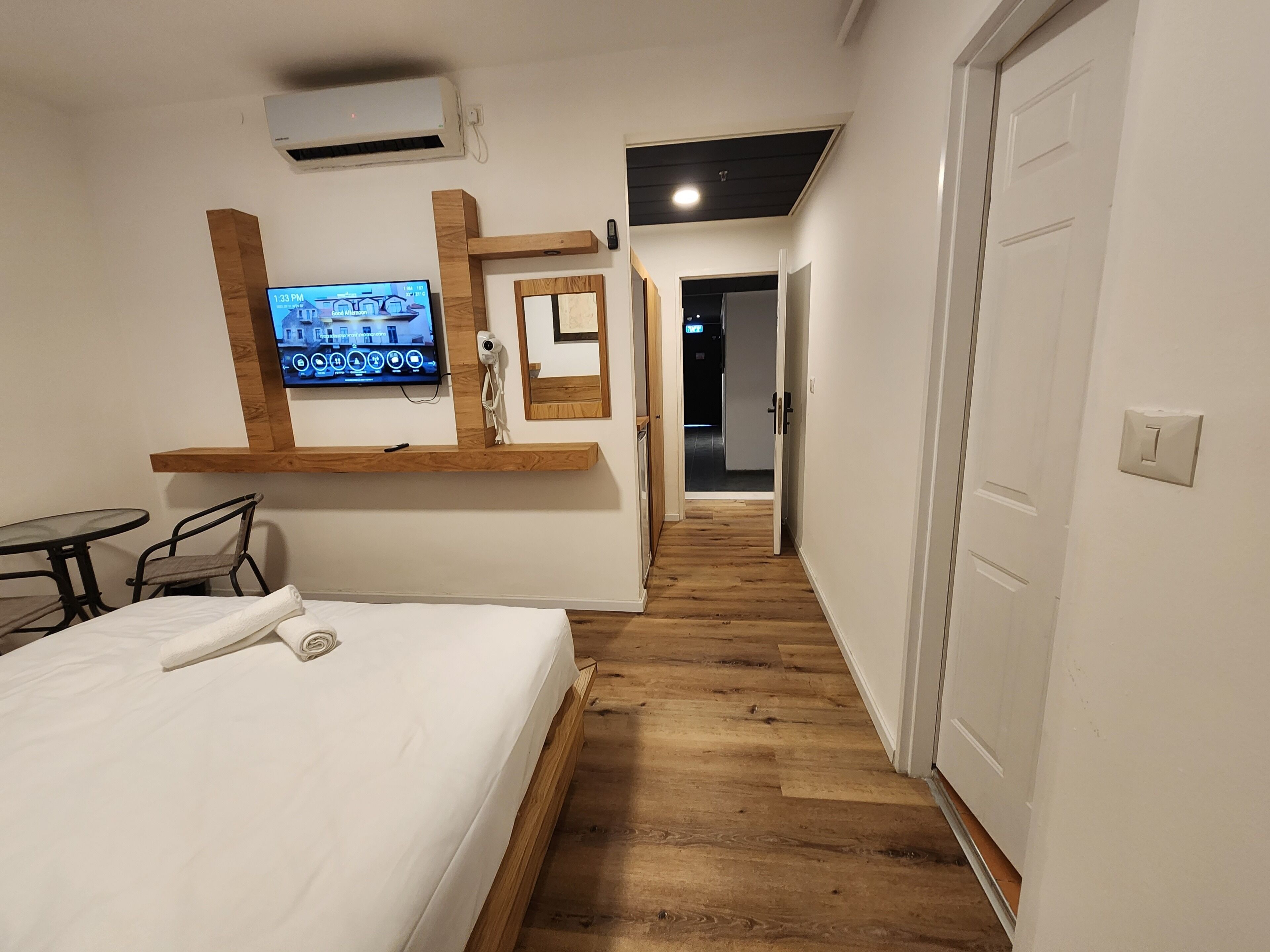 A hotel room with a bed, a TV, a desk, and a mirror.