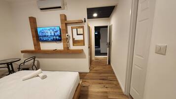 A hotel room with a bed, a TV, a desk, and a mirror.