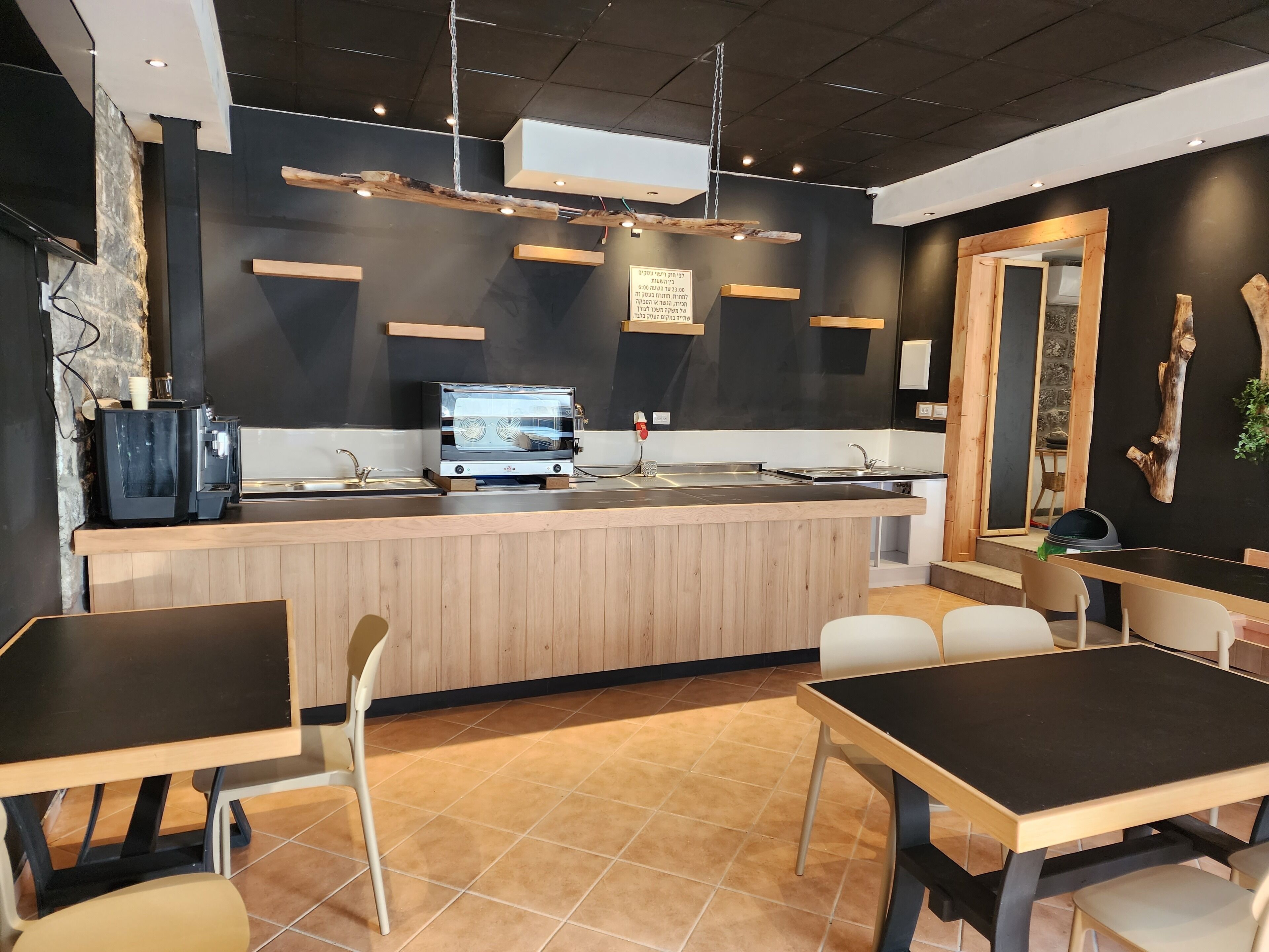 A modern cafe with a wooden counter, black and white decor, and a seating area with tables and chairs.