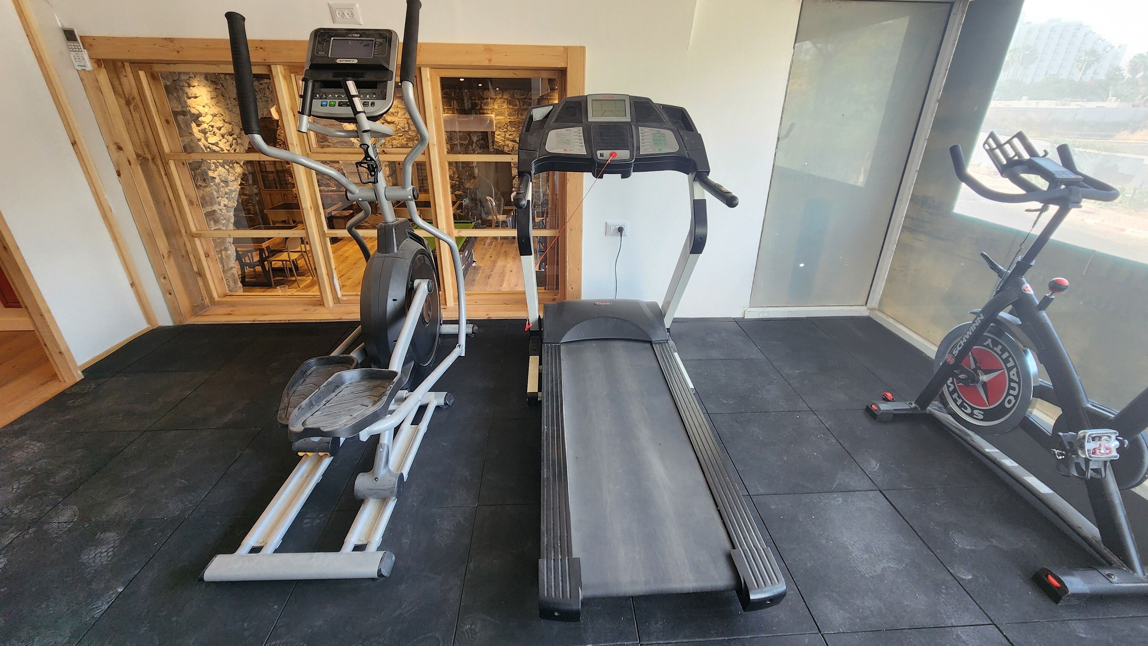 Une salle de sport équipée d’un tapis de course, d’un vélo elliptique et d’un vélo d’appartement.