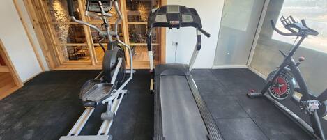 Une salle de sport équipée d’un tapis de course, d’un vélo elliptique et d’un vélo d’appartement.