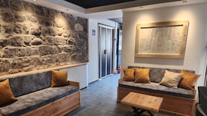 A modern lounge area with stone walls, two sofas with cushions, and a wooden coffee table. - Tiberia hotel (Tiberias)