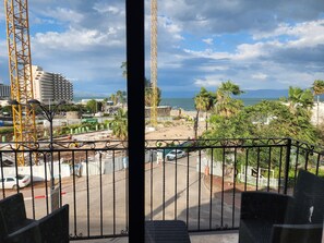 A balcony with a view of a construction site, palm trees, and a building with a sign that reads "tenoardo." - Tiberia hotel (Tiberias)