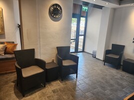 A lobby with wicker chairs, a clock, and a reception area.