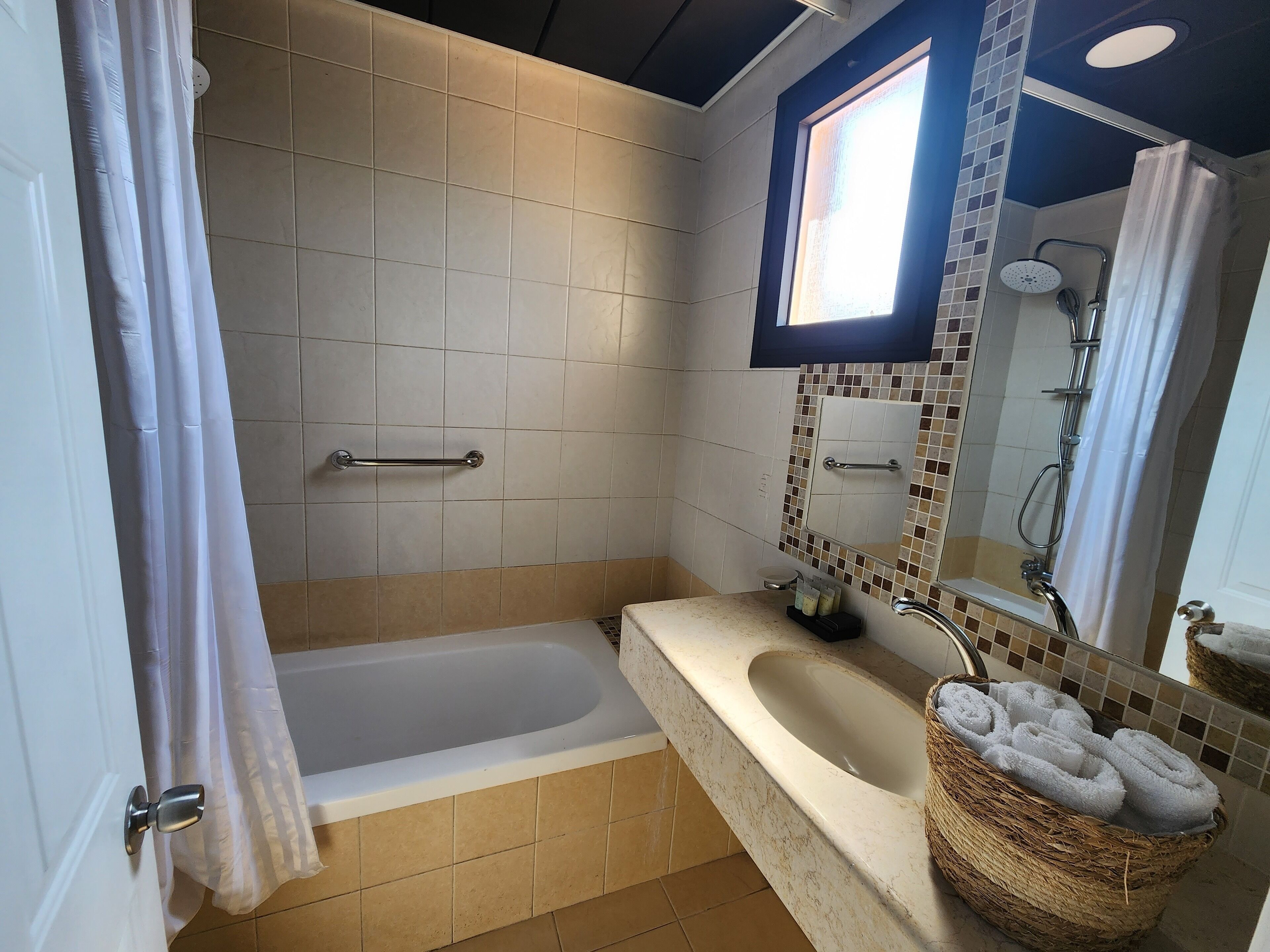 Une salle de bain avec une baignoire, un lavabo, un miroir et une douche.