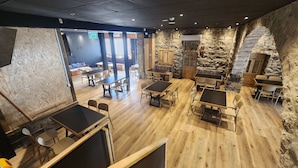 A restaurant with wooden tables and chairs, stone walls, and a view of the outside. - Tiberia hotel (Tiberias)