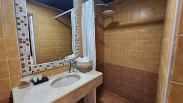 Un baño con lavabo, espejo, ducha y paredes de azulejos.