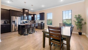A modern kitchen with dark cabinetry, stainless steel appliances, and a central island with bar stools. - Your Home Away From Home in the Texas Hill Country, Georgetown TX (Georgetown)