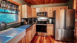 Une cuisine dotée de meubles en bois, d’un réfrigérateur en acier inoxydable, d’un four à micro-ondes, d’une cuisinière et d’un évier.