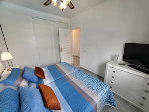 A bedroom with a bed, pillows, a TV, and a dresser.