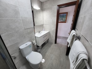 A modern bathroom with a toilet, sink, and towel rack.
