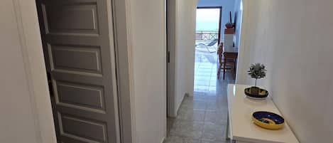Um corredor com porta que dá para uma varanda com vista para o mar.