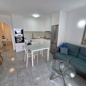 A compact living space with a kitchenette, dining area, and seating area. - Victoria Court II (Los Cristianos)