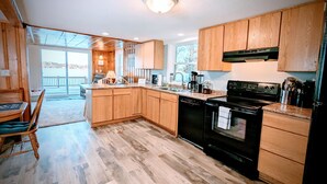 A modern kitchen with wooden cabinets, a black stove, and a large window overlooking a balcony.