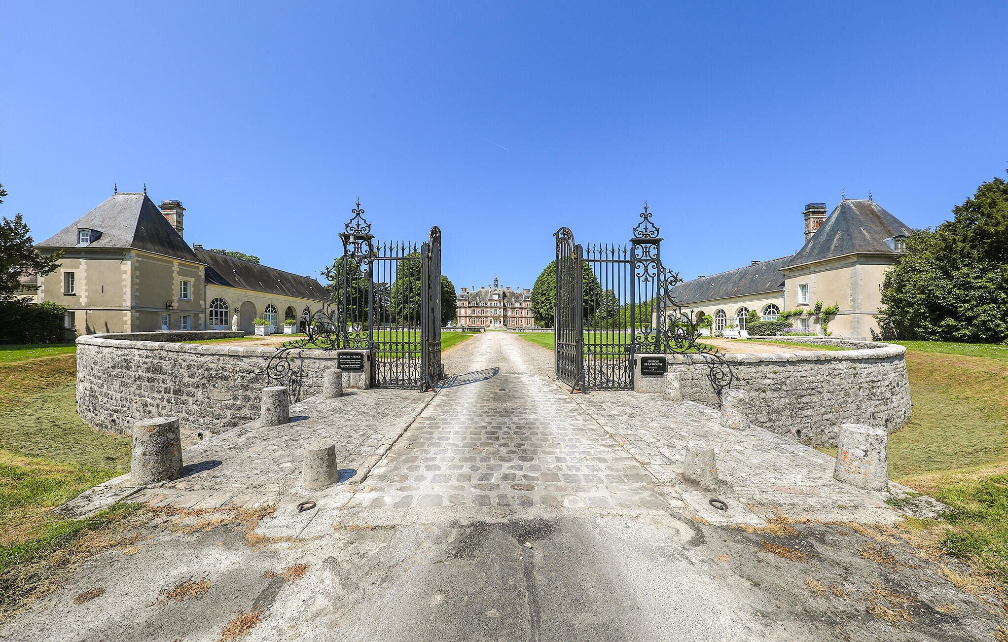 Un bâtiment historique doté d’un portail d’entrée central, de murs en pierre et d’un chemin pavé menant à l’entrée.