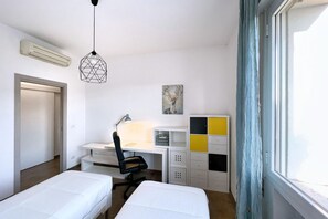 Un dormitorio con dos camas, un escritorio, una silla y una ventana con cortinas.