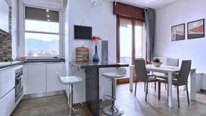 Une cuisine moderne avec un coin repas, comprenant un tabouret de bar, une table à manger avec des chaises, un téléviseur et une fenêtre avec vue.