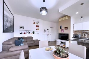 Una sala moderna con sofá, mesa de comedor y zona de cocina con microondas y tostadora.